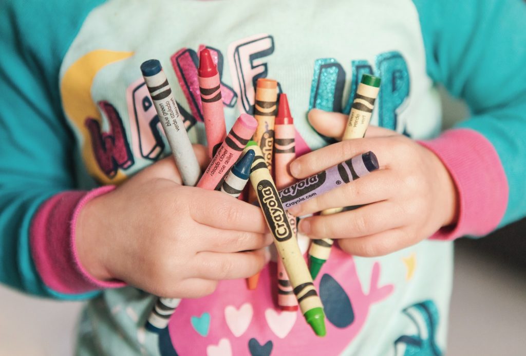 little kid holding crayons