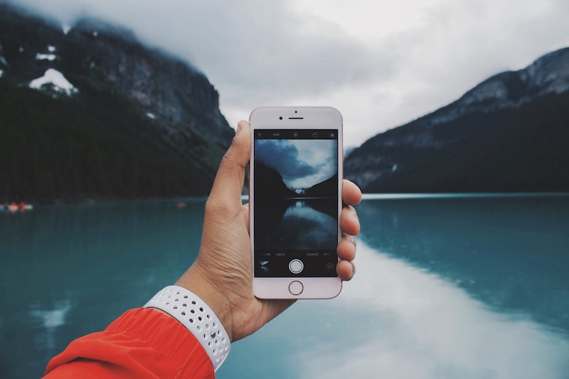 holding-iphone-in-front-of-blue-lake